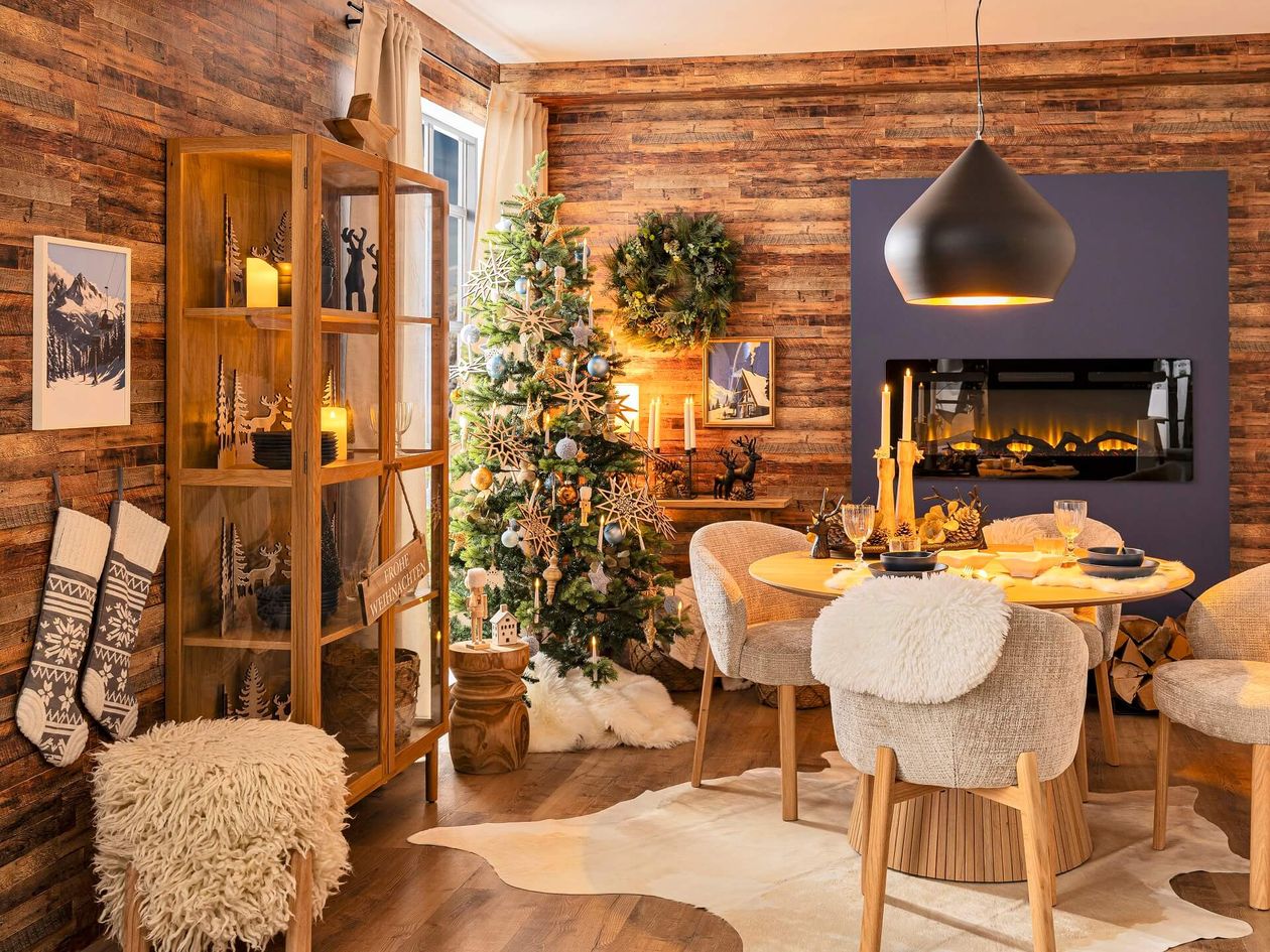 Gemütliches Esszimmer mit Weihnachtsbaum, Holzmöbeln, festlicher Dekoration und brennendem Kamin, der eine warme Feiertagsatmosphäre schafft.