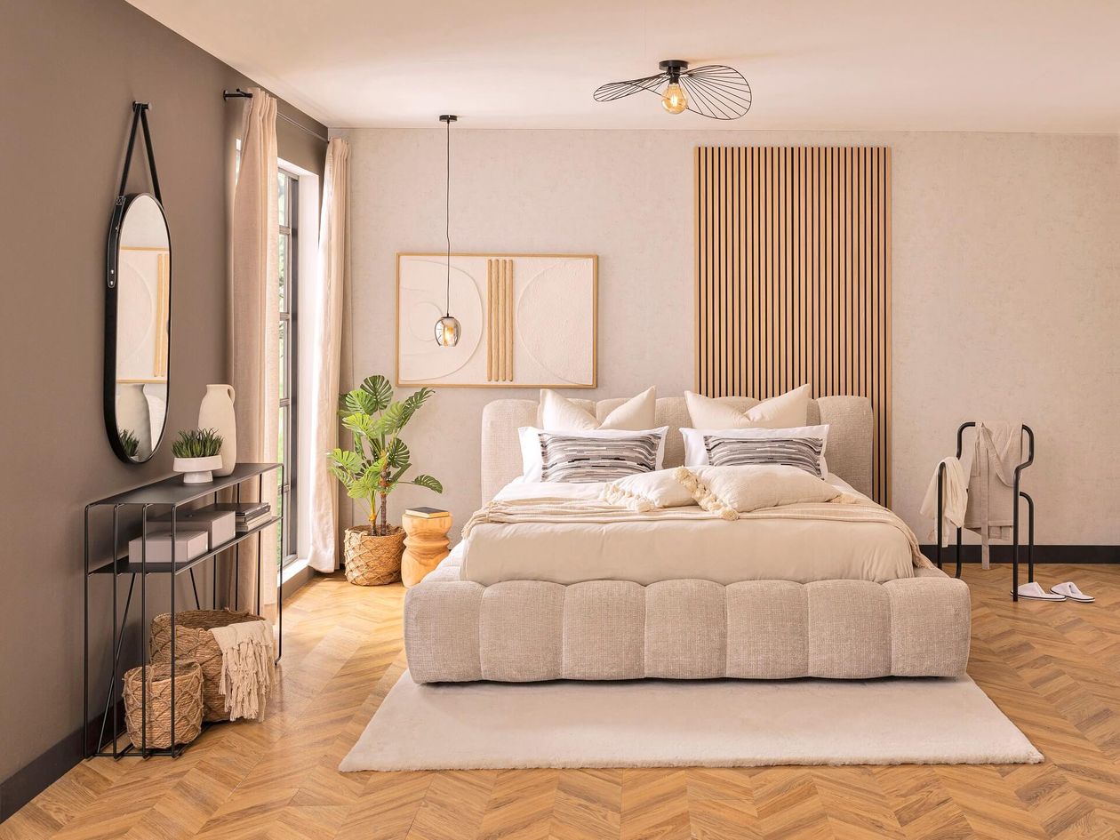 Modernes Schlafzimmer mit großem, beigem Polsterbett und heller Gestaltung.