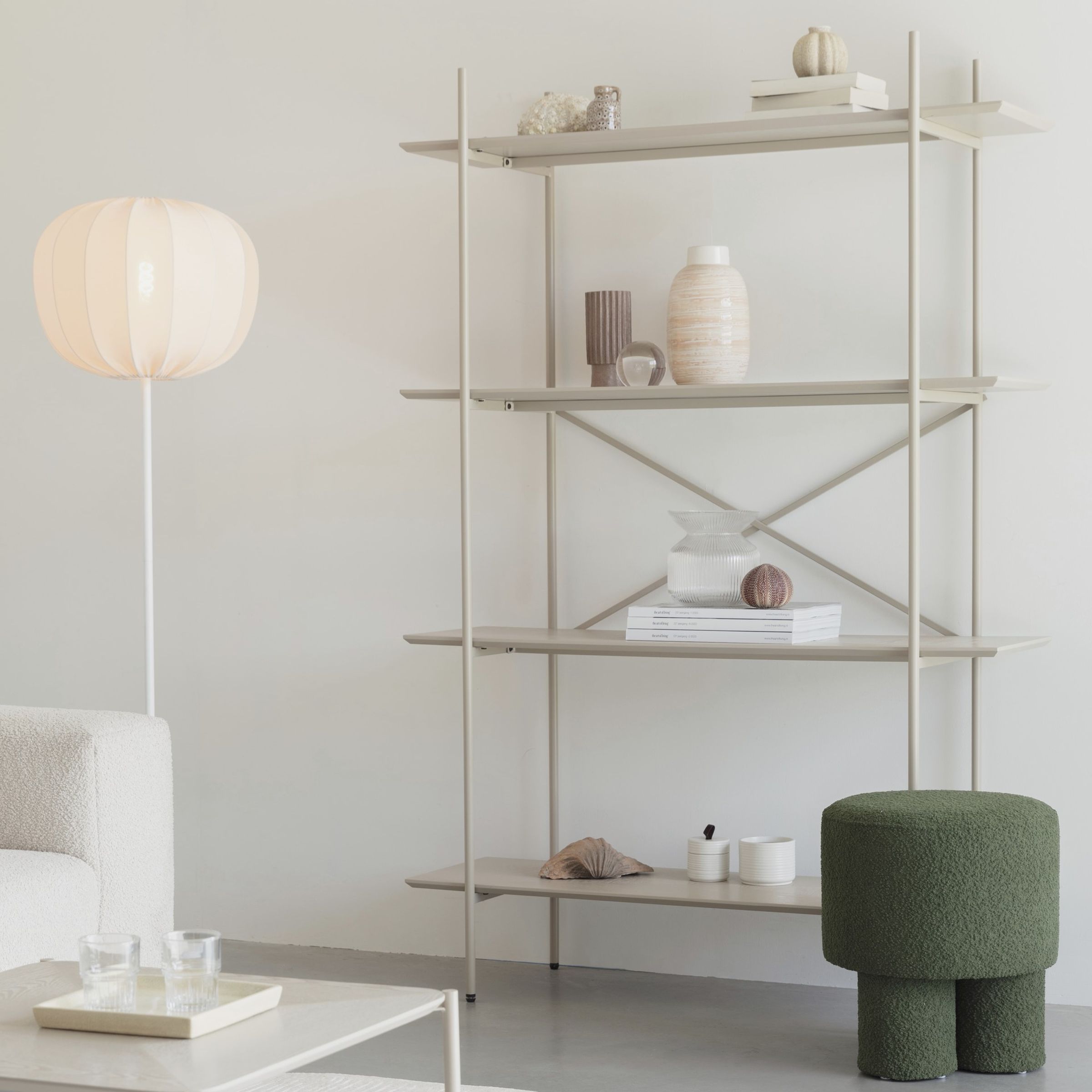 Wandregal Marcio der Marke Zuiver aus beigem Metall in einer weiß gehaltenen Einrichtung mit moosgrünem Hocker als Farbkontrast