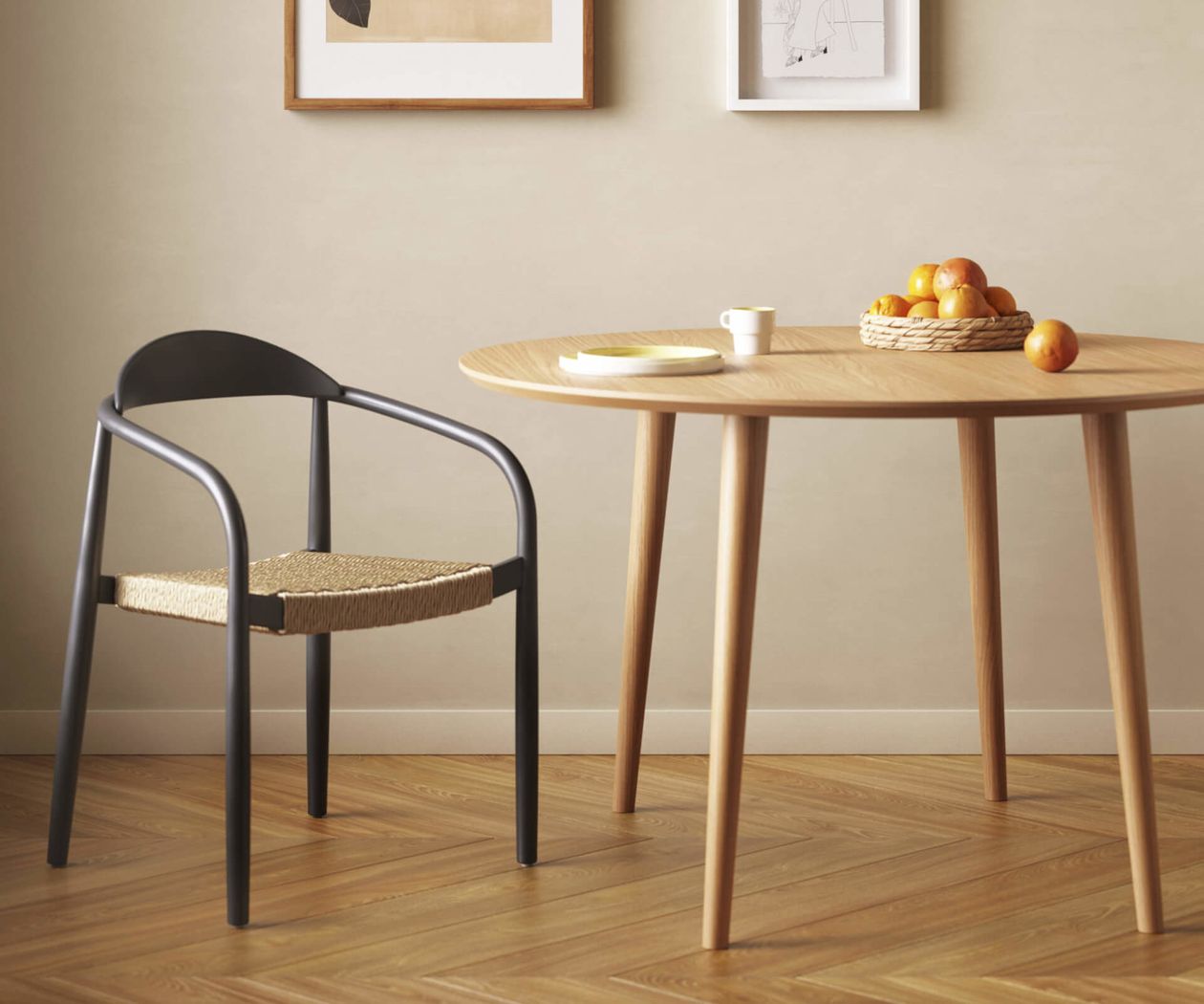 Ein moderner Essbereich mit einem runden Holztisch, einem schwarzen Stuhl, zwei Wandbildern und einem Korb mit Orangen.