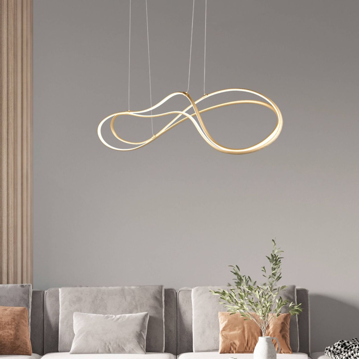 Pendelleuchte aus gebogenem Metall in Gold über grauer Couch.