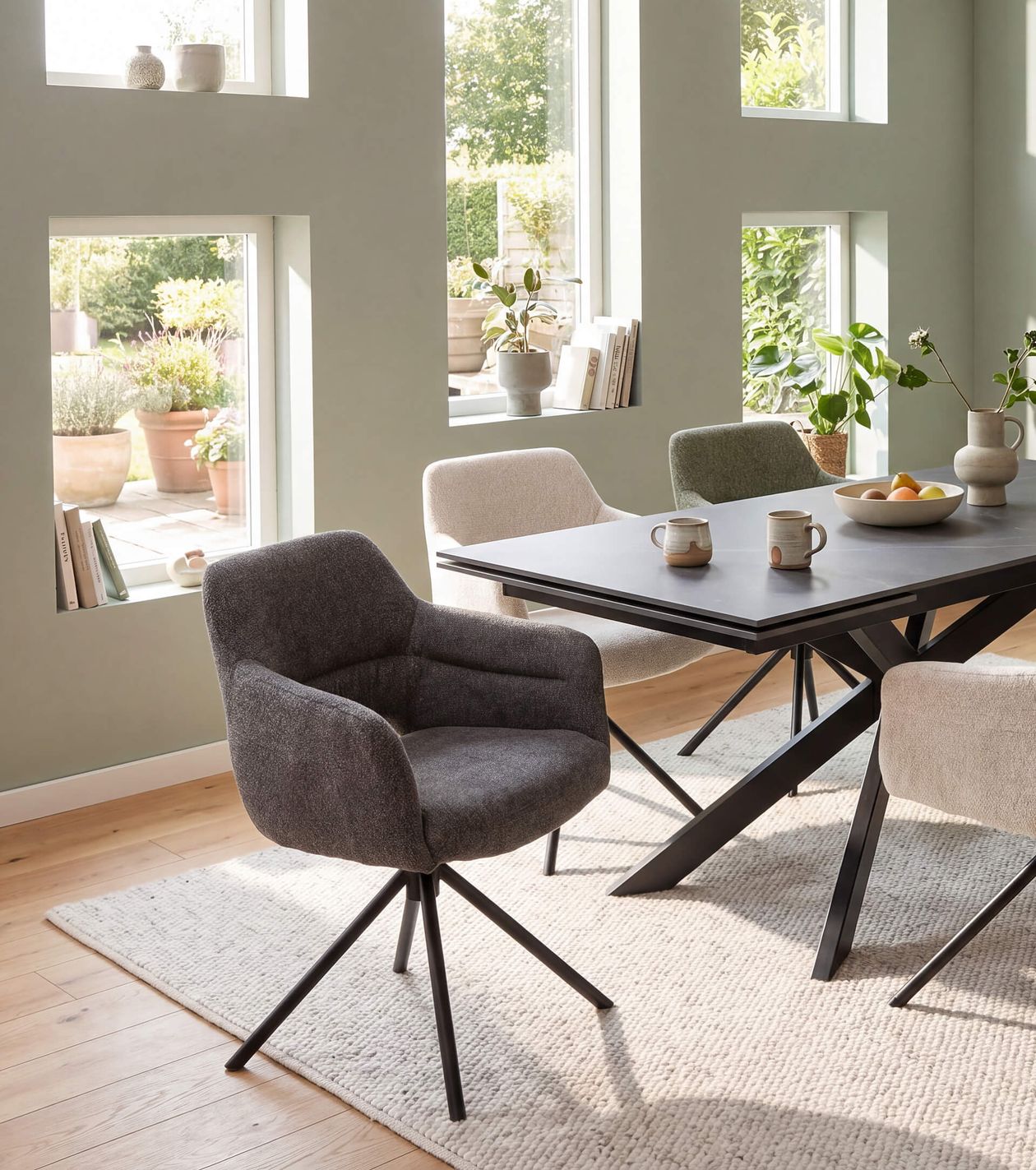 Esszimmer mit modernem Tisch, vier Stühlen, Fenster mit Blick ins Grüne und Dekoration; helle, gemütliche Atmosphäre.