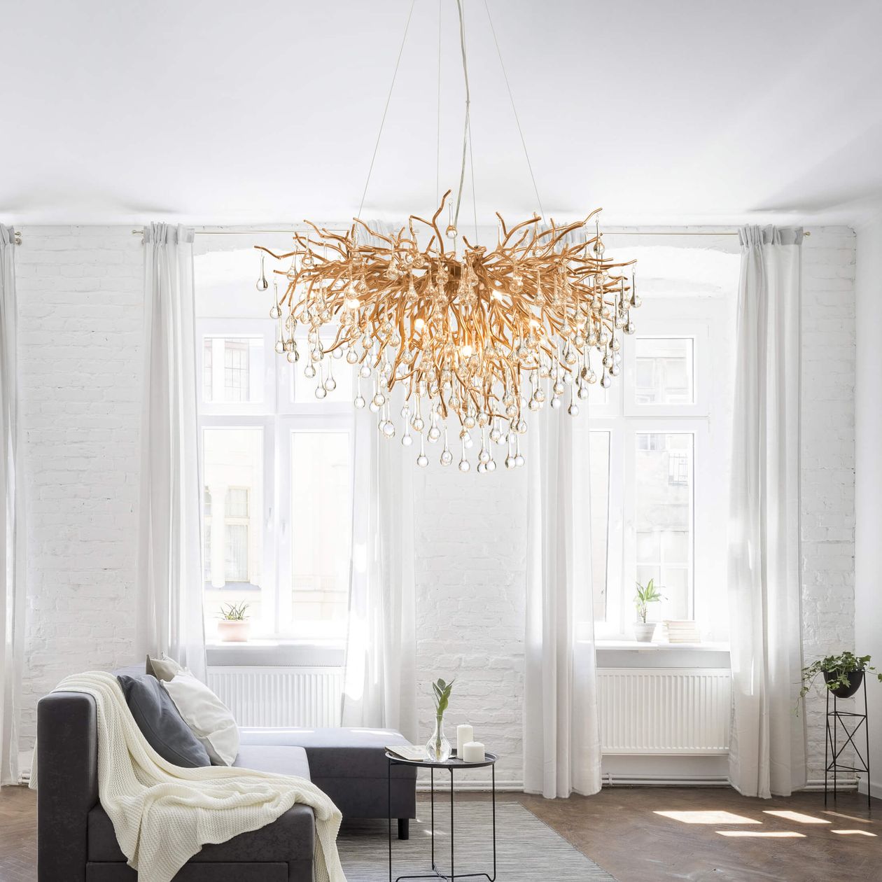 Goldener Kronleuchter über einem schlichten Interieur mit einer dunklen Couch.