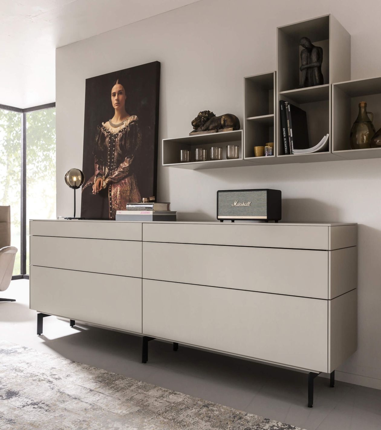 Graue, breite Kommode, auf der eine Musikbox steht. Darüber befinden sich kubische Regale und ein gemaltes Bild.