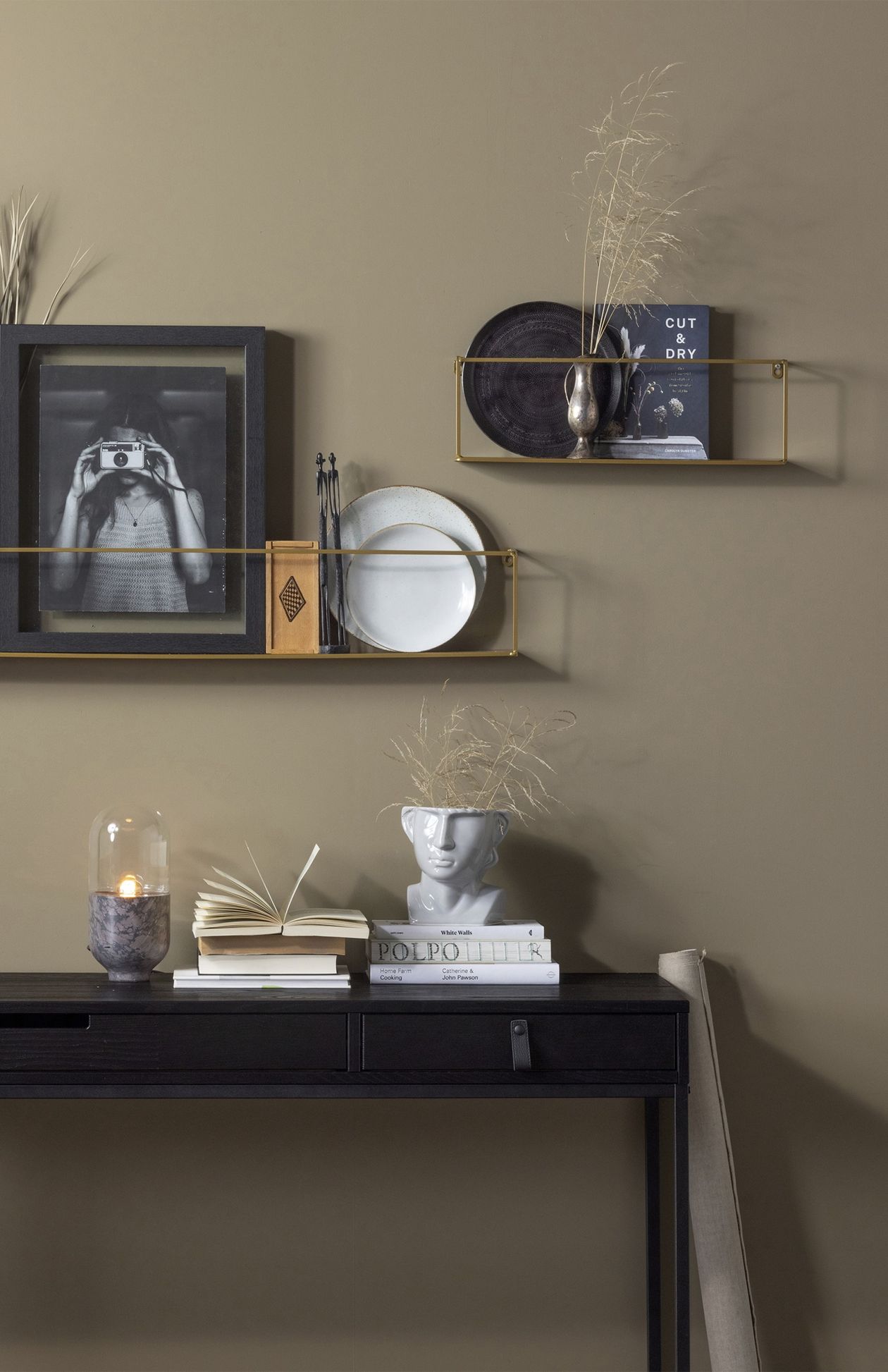 Wandregal Meert in Gold aus Metall vor einer sandfarbenen Wand mit moderner Dekoration