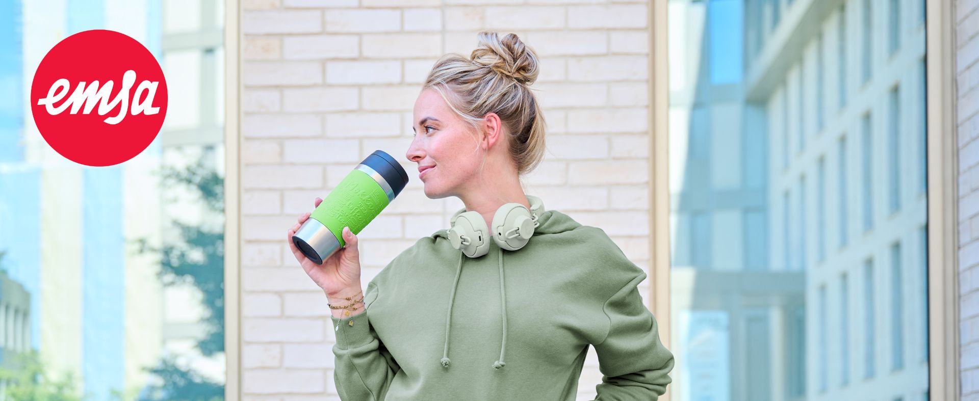 Eine Frau hält den grünen Isolierbecher Travel Mug von Emsa aus Edelstahl.