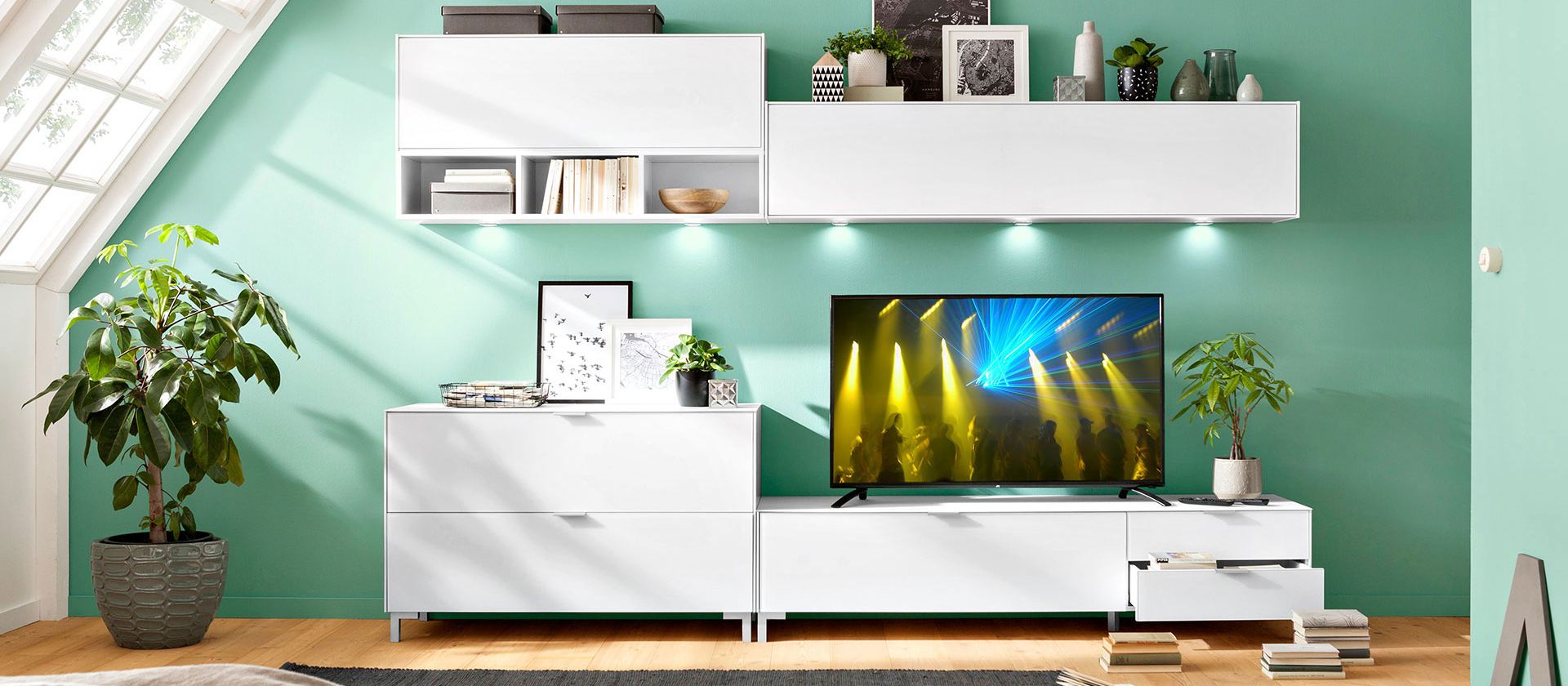 Weiße Wohnwand Chicago von set one by Musterring in einem Wohnzimmer mit Dachschräge und einer grünen Wand