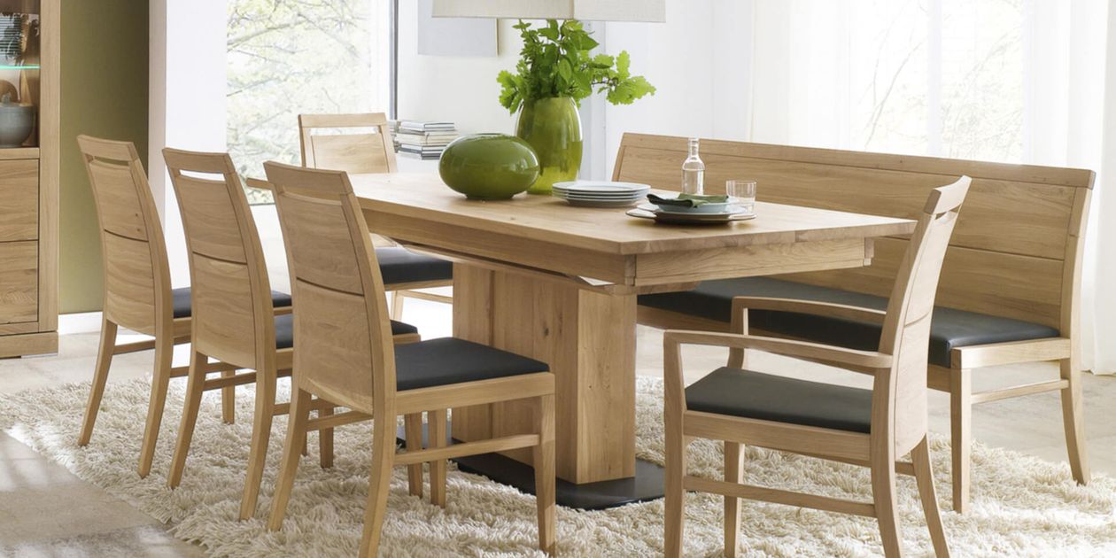 Holzbank mit hoher Rückenlehne und dunklem gepolstertem Sitz, umrahmt von hellem Holz. Schlichtes und modernes Design mit klaren Linien.