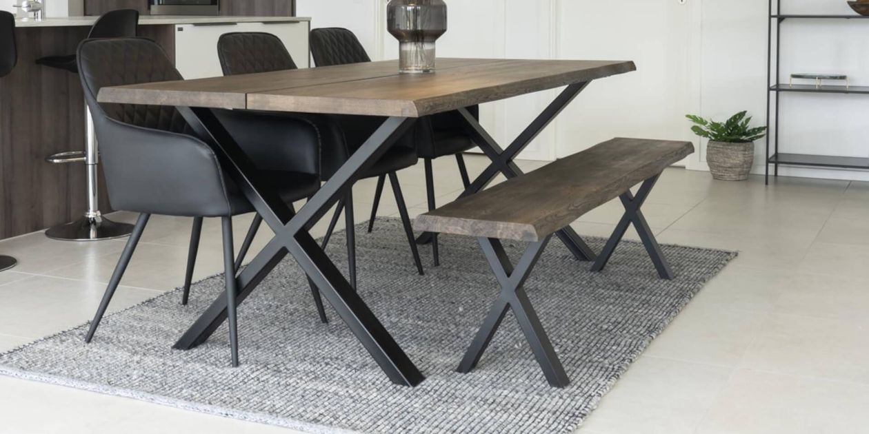 Eine Holzbank mit einer flachen Sitzfläche aus Naturholz und schwarzen Metallbeinen. Die Bank hat ein minimalistisches und modernes Design.