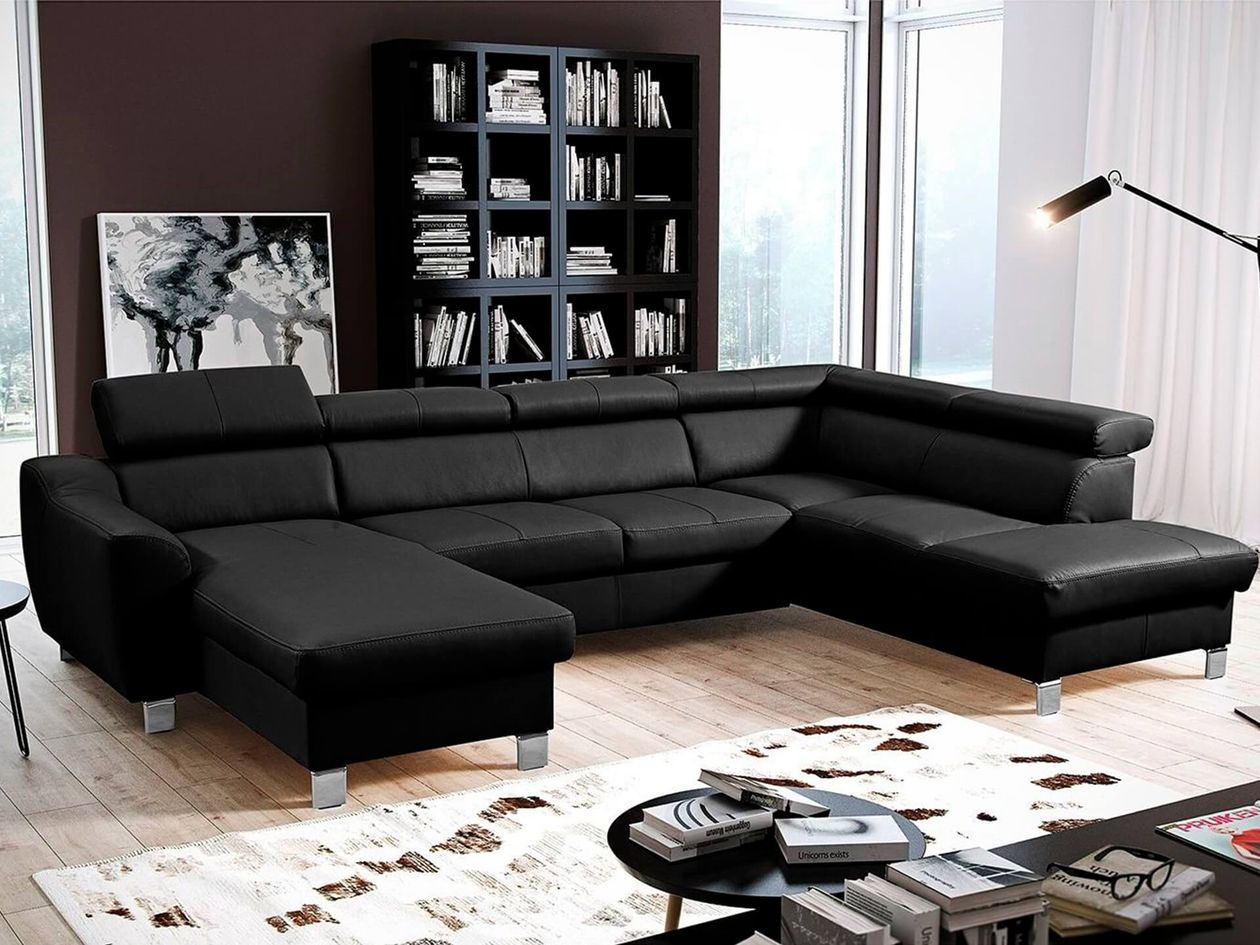Große U-förmige Wohnlandschaft aus schwarzem Leder mit verstellbaren Kopfstützen und Chromfüßen in einem Wohnzimmer mit dunklem Bücherregal und bodentiefen Fenstern.