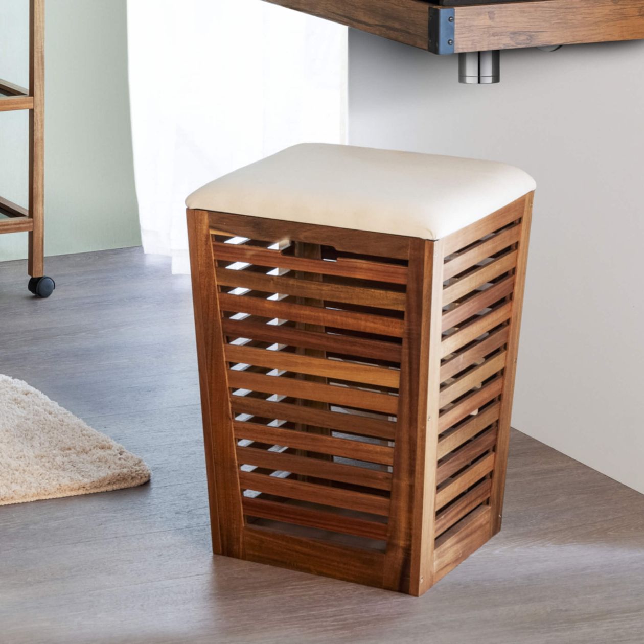 Wooden stool with lattice design and white cushioned seat in a modern room with wooden floor and a small rug.