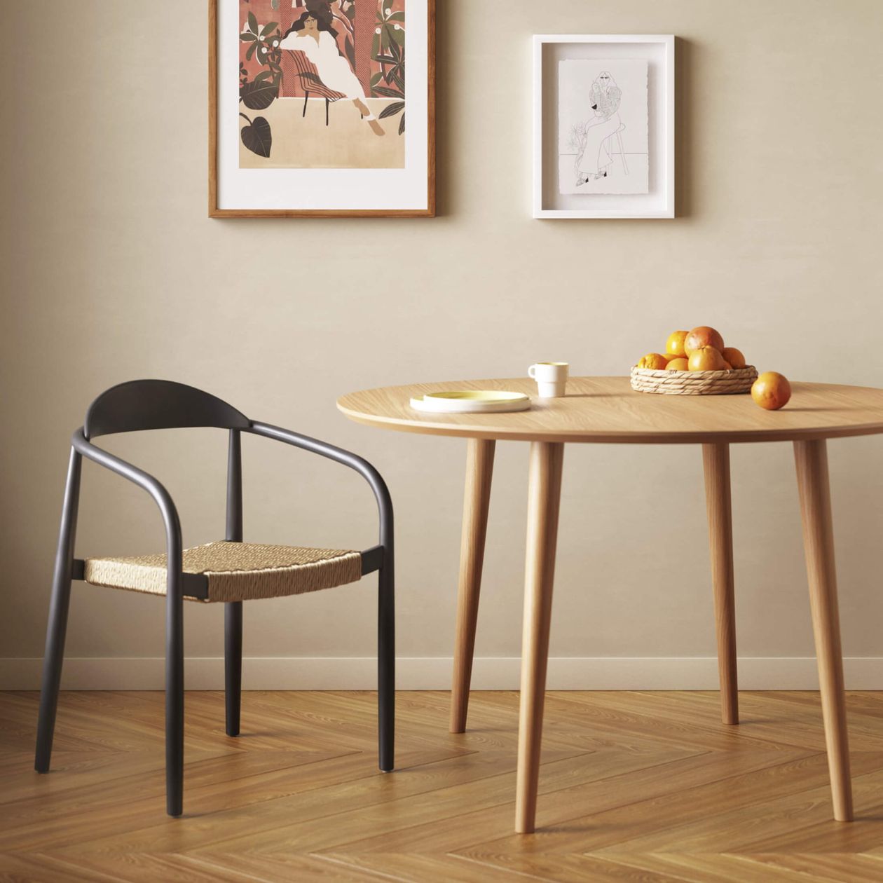 Ein minimalistischer Essbereich mit einem Holztisch, einem schwarzen Stuhl, einem Korb mit Orangen, einer Tasse und einem gerahmten Kunstwerk an hellen Wänden.