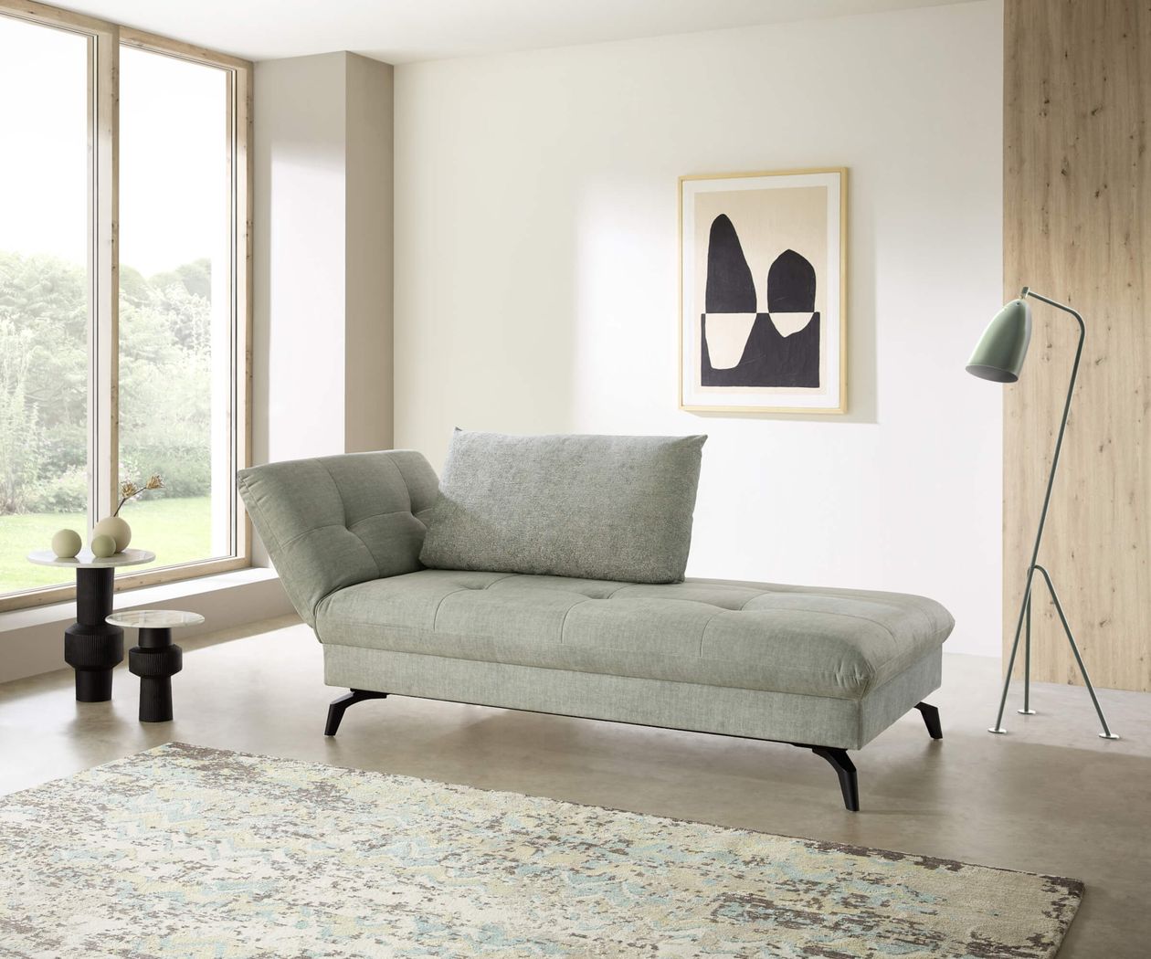 Modernes Wohnzimmer mit grauem Sofa, abstrakter Kunst an der Wand, Stehlampe, kleinem Beistelltisch und großem Fenster mit Gartenblick.