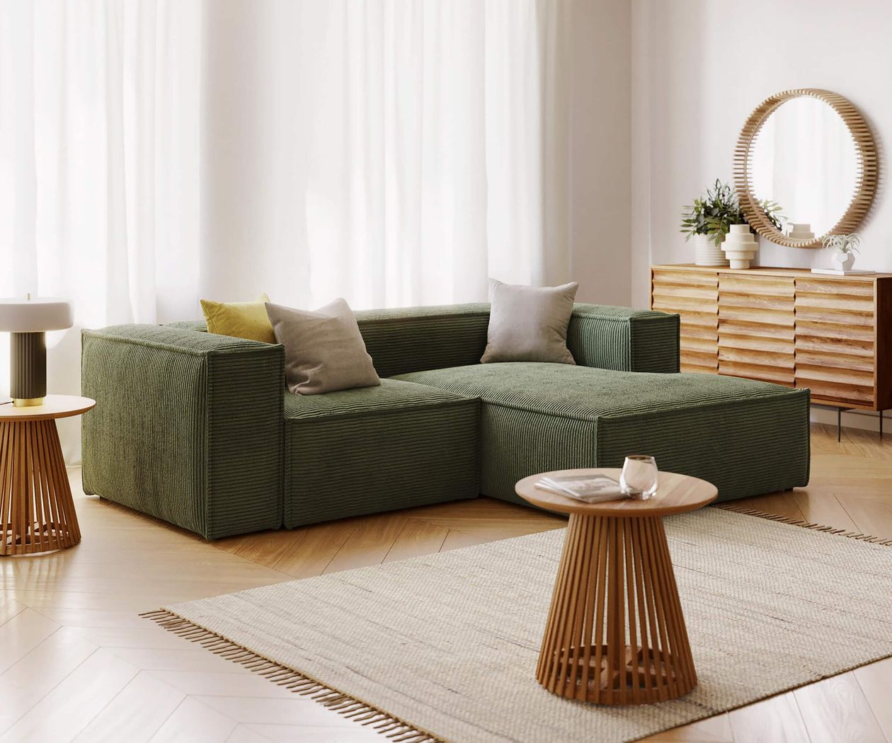Geräumiges Wohnzimmer mit grünem Sofa, Holz-Couchtisch, Kommode mit rundem Spiegel und großen Fenstern mit weißen Vorhängen.