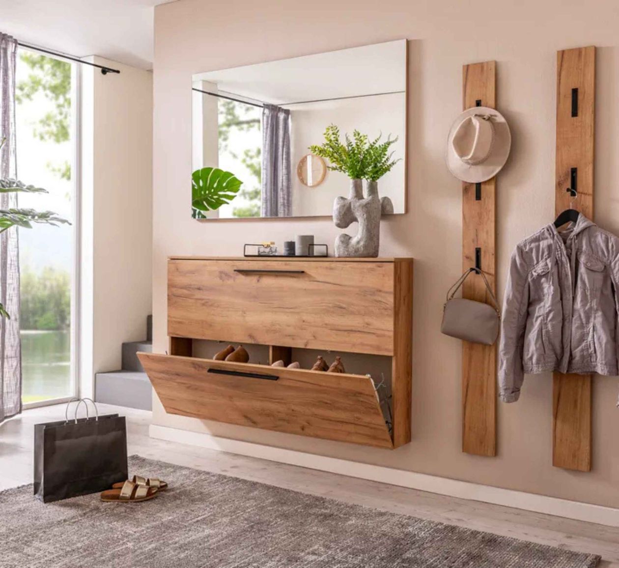 Moderner Flur mit Holzschuhschrank, Spiegel, Haken mit Jacke und Hut, Pflanze auf dem Schrank, Sandalen und Einkaufstasche auf Teppich.