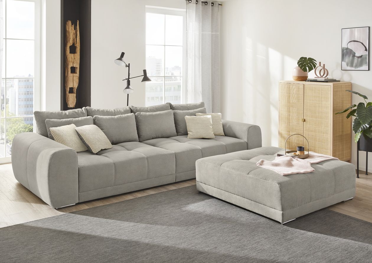 graues Cord-Bigsofa stehend auf einem grauen Teppich