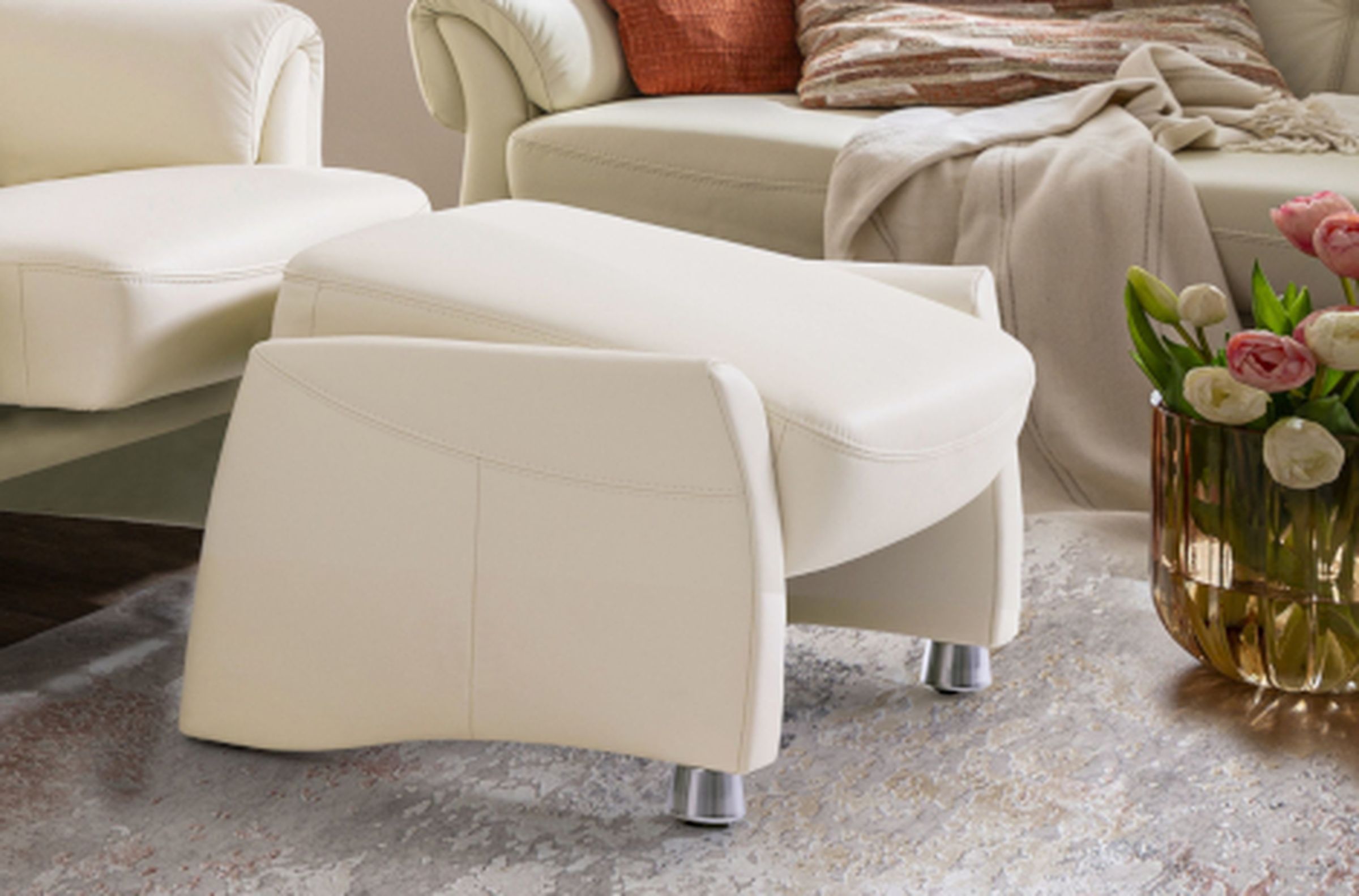 Der weiße Hocker des Ledersofas Toulon aus den SEGMÜLLER WERKSTÄTTEN in geneigter Position