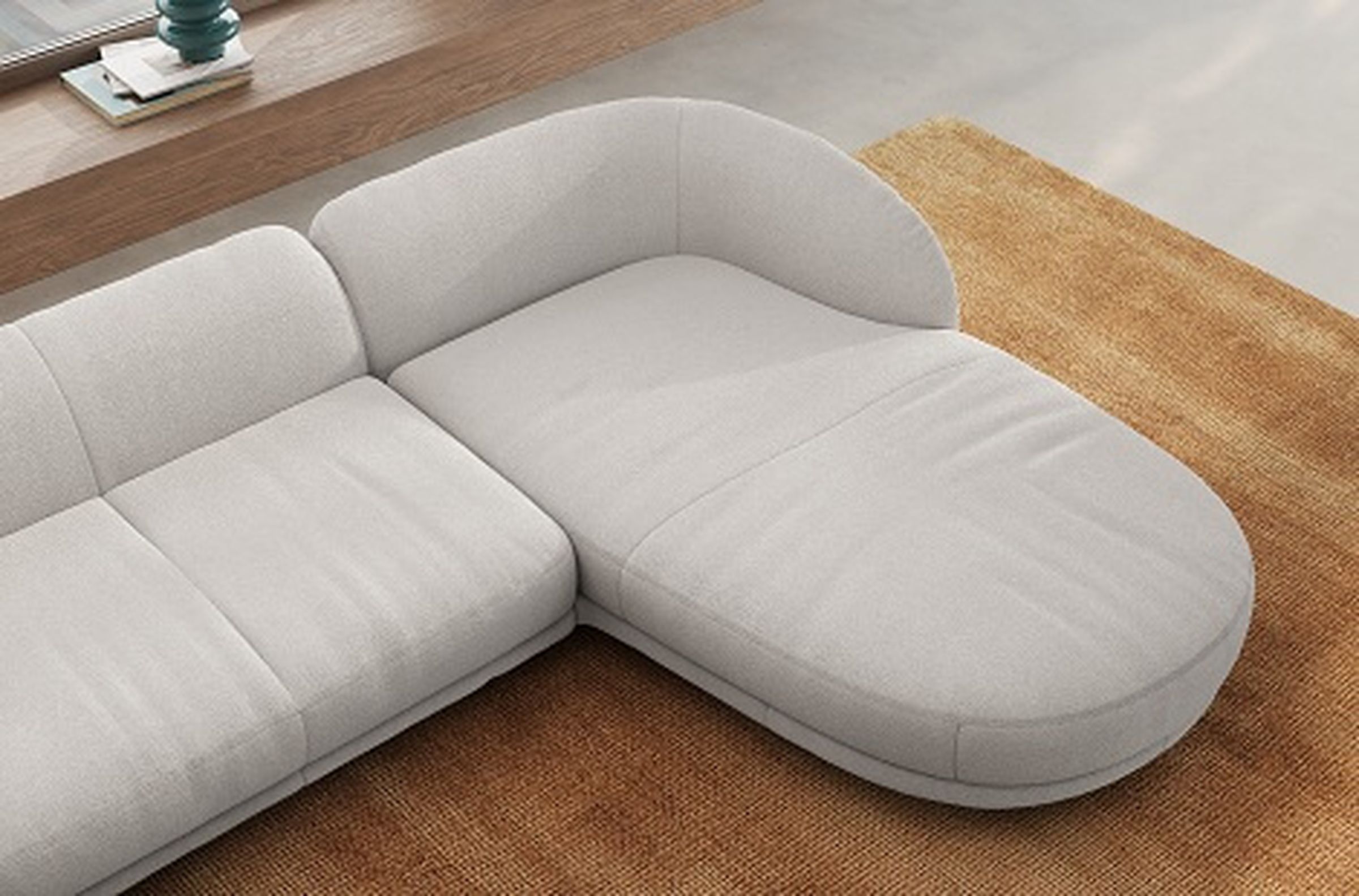 Modernes weißes Sofa mit abgerundeter Chaiselongue auf einem braunen strukturierten Teppich in einem minimalistischen Wohnzimmer.