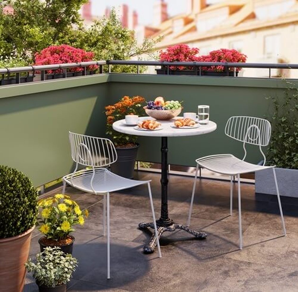 Ein Balkon mit einem runden Tisch für zwei Personen, an dem Obst, Gebäck und Getränke bereitstehen. Umgeben von Topfpflanzen und Blumen unter einem sonnigen Himmel.