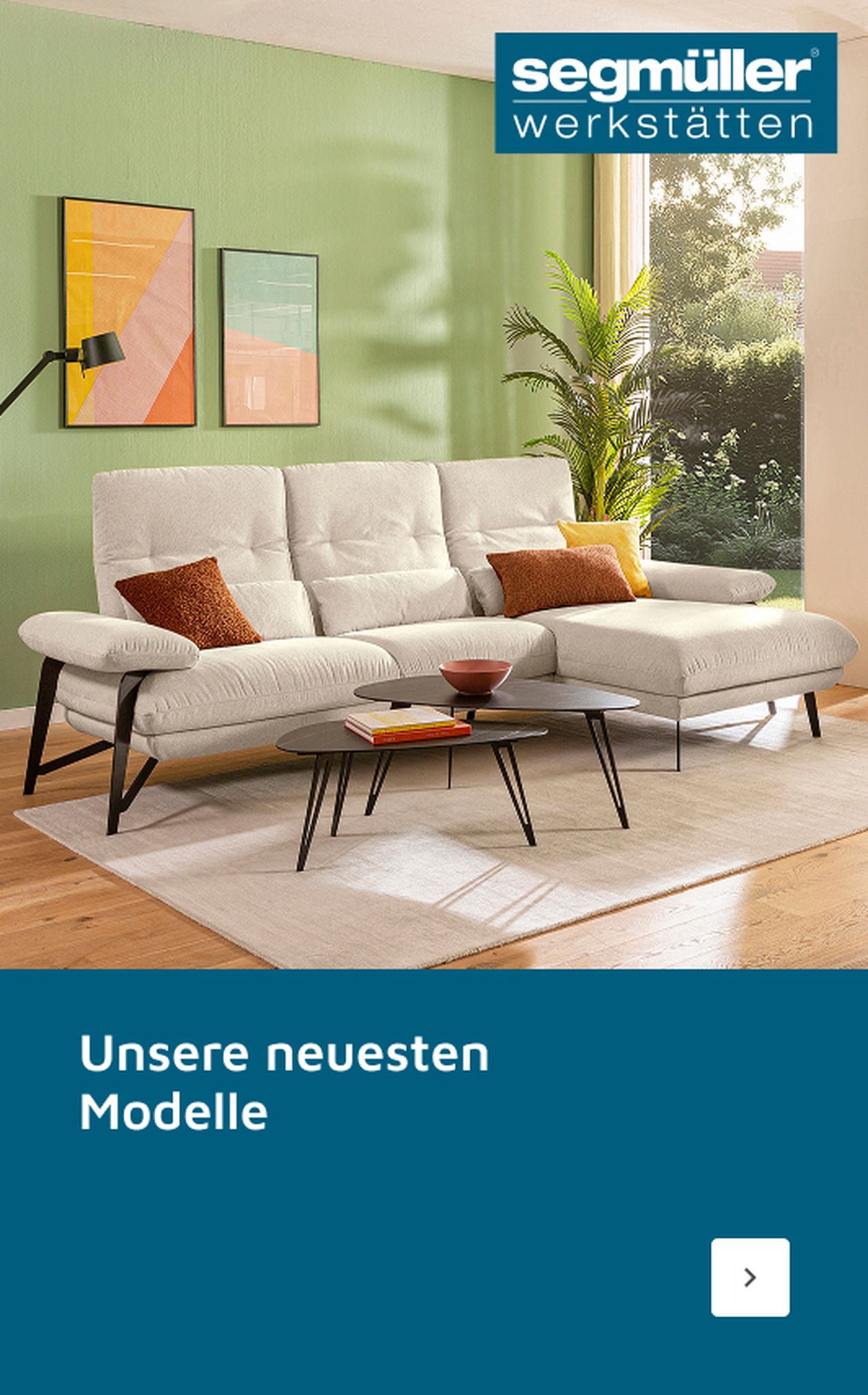 Modernes Wohnzimmer mit weißem Sofa, bunten Kissen, runden Couchtischen und abstrakter Wandkunst. Text: „Unsere neuen Jubiläumsmodelle.“
