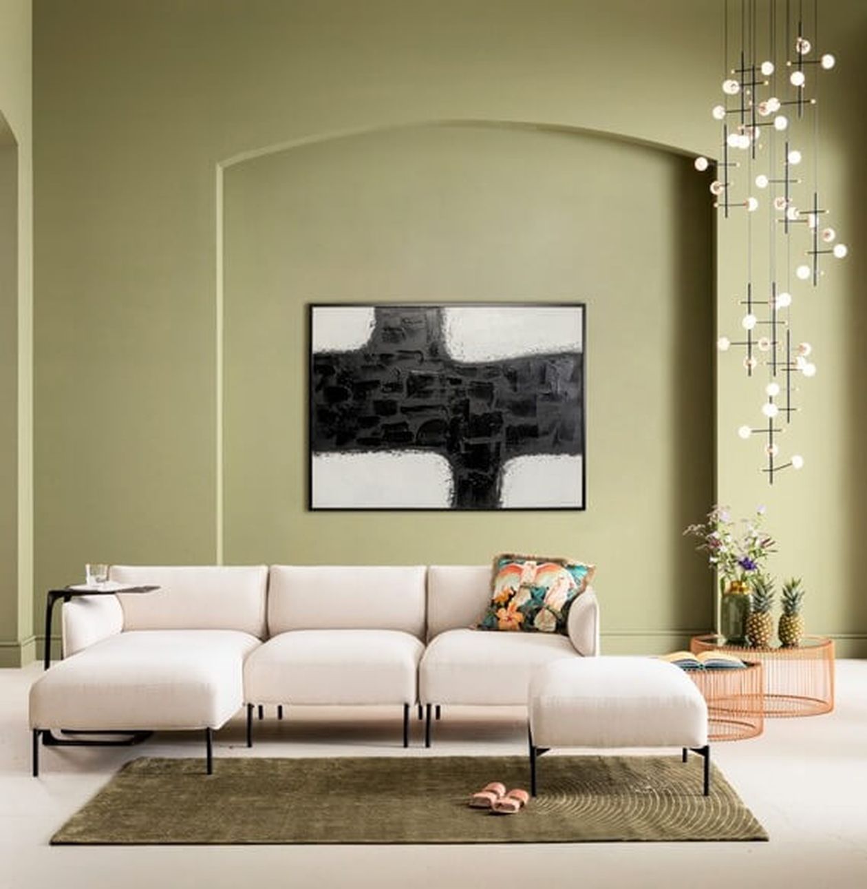 Modernes Wohnzimmer mit weißem Sofa, abstrakter Wandkunst, Hängelampen und einer grünen Akzentwand. Couchtisch mit Pflanzen und Dekor.