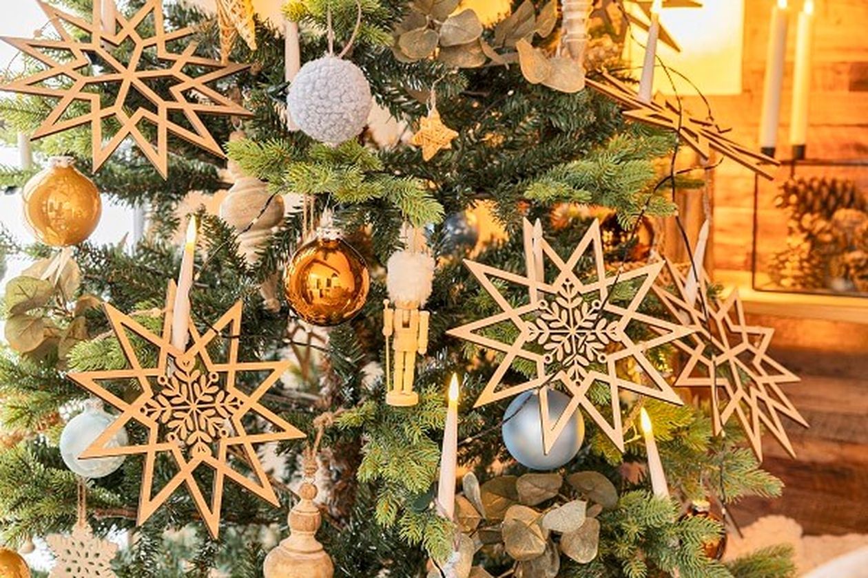 Der Weihnachtsbaum ist mit großen hölzernen Sternornamenten, goldenen Kugeln, Kerzen und Tannenzapfen geschmückt und sorgt für eine festliche und gemütliche Atmosphäre.