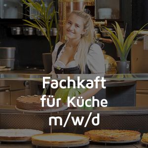 Eine Fachkraft für Küche präsentiert lächelnd eine Torte.