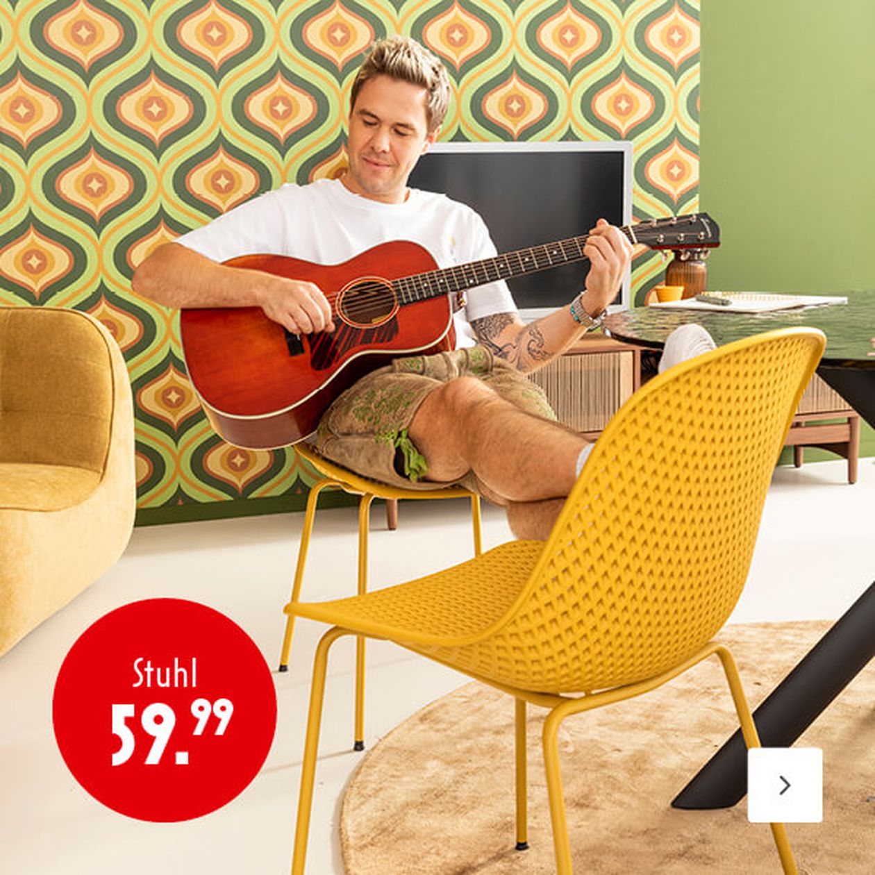 Mann spielt Gitarre in einem Retro-Zimmer mit einem gelben Stuhl und Vintage-Tapete. Preisschild: „Stuhl 59,99“.