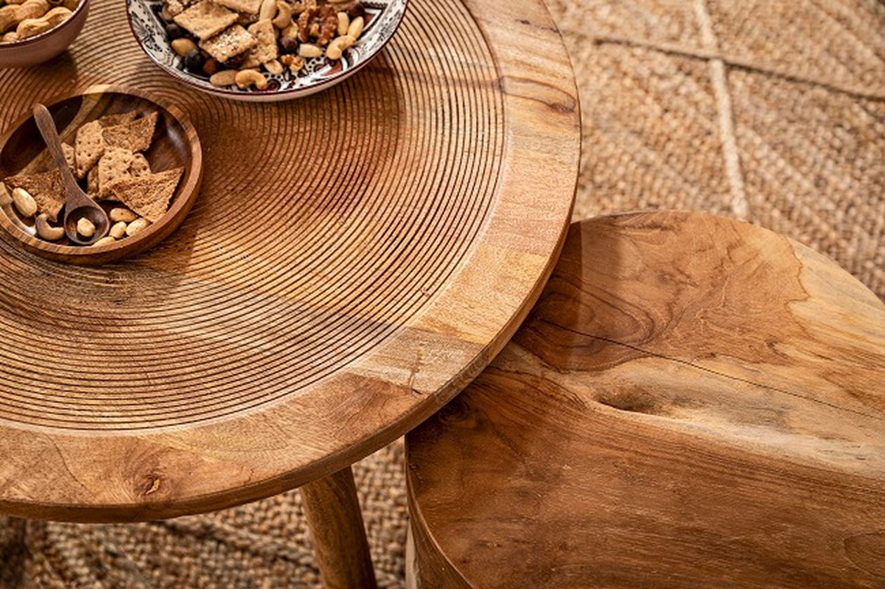Holztisch mit Snacks wie Crackern und Nüssen in Schüsseln. Die natürliche Maserung und Textur der Tischplatte und des passenden Stuhls sind sichtbar.