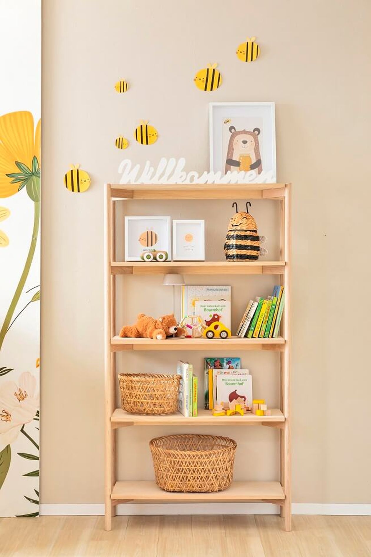 Bücherregal aus hellem Holz mit freundlicher, kindlicher Deko.