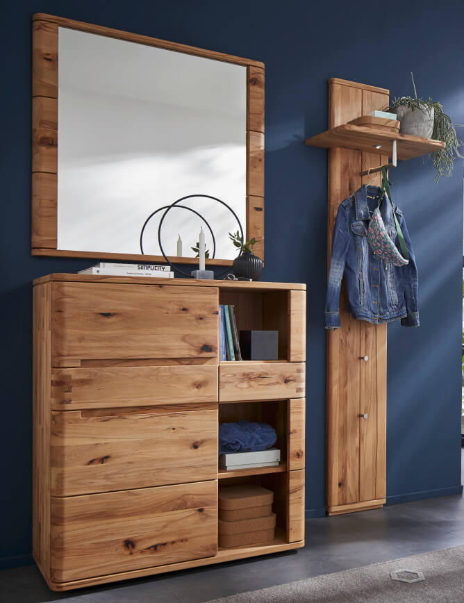 Holzkommode mit offenen Regalen, einem Garderobenständer und einem großen Spiegel an einer blauen Wand.