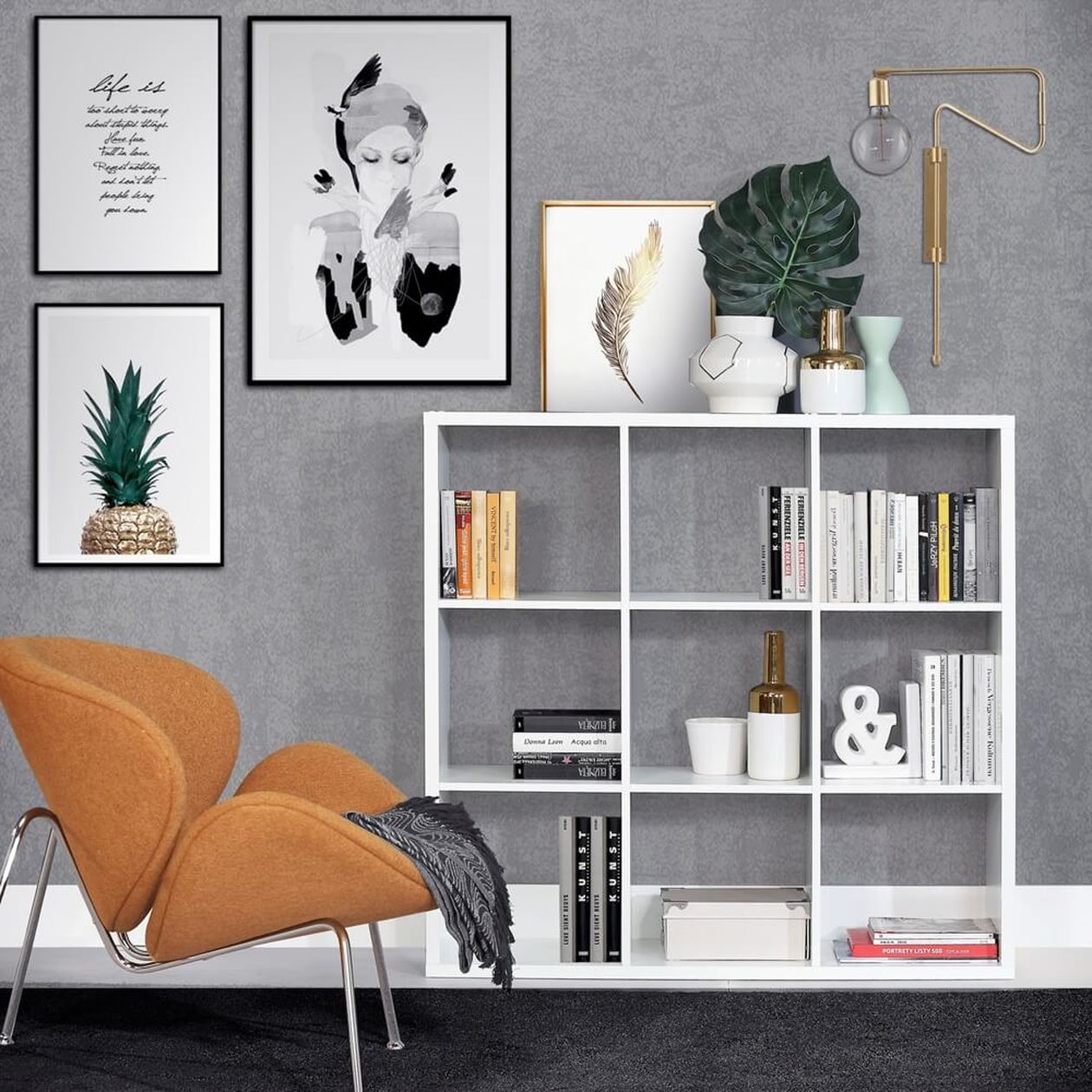 Modernes Wohnzimmer mit einem weißen Bücherregal, einem orangefarbenen Stuhl, Wandkunst, einer Topfpflanze und Dekorationsgegenständen an einer grauen Wand.