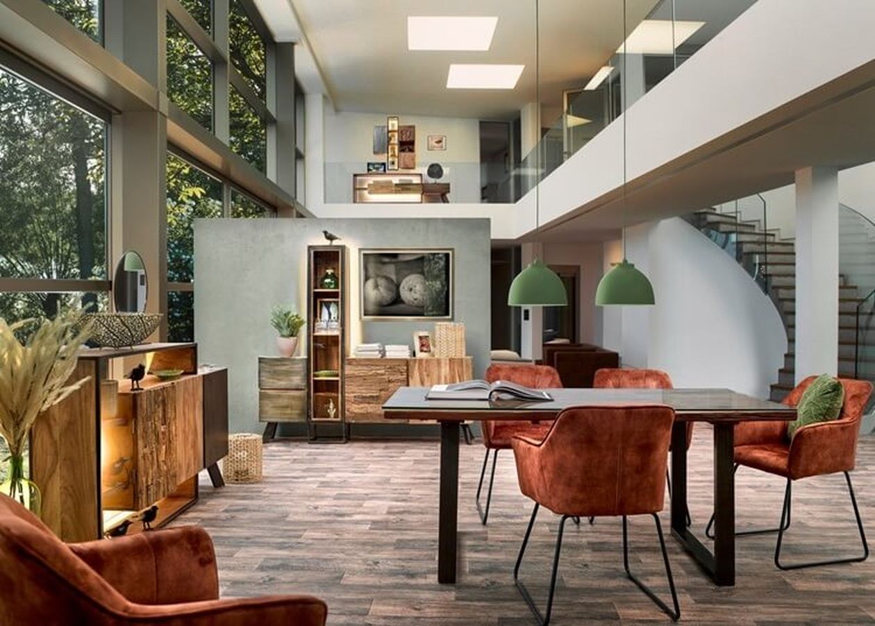 Moderner Essbereich mit Holztisch, rostfarbenen Stühlen, grünen Pendelleuchten und großen Fenstern. Eine Treppe und Pflanzen runden das Dekor ab.