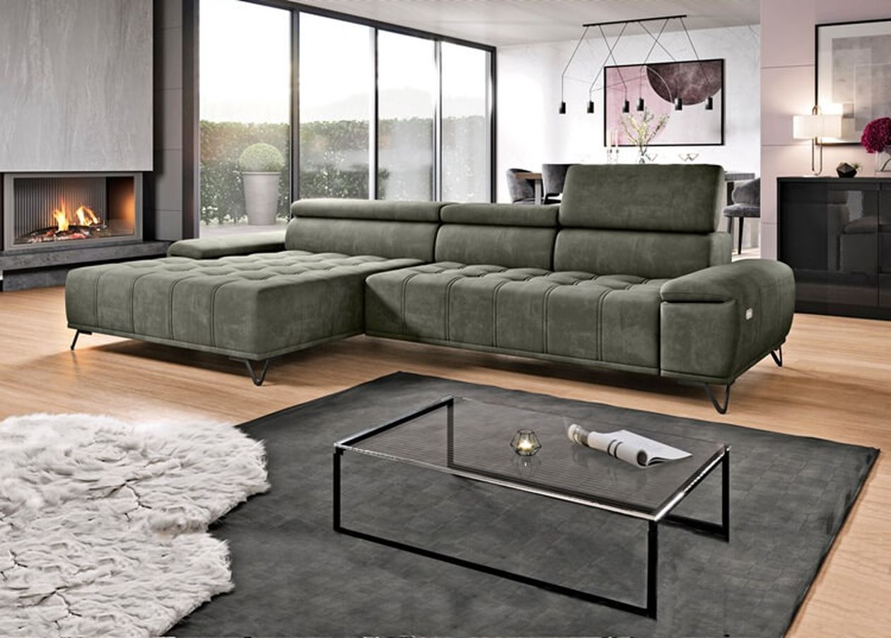Modernes Wohnzimmer mit einem grünen Sofa, einem Couchtisch aus Glas, einem grauen Teppich und einem Kamin. Große Fenster sorgen für natürliches Licht.