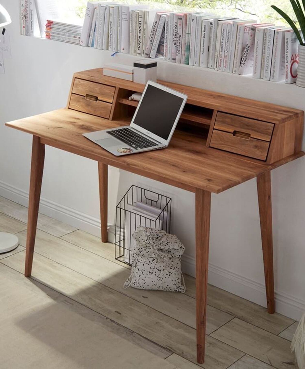 Schreibtisch aus massivem Akazienholz mit Aufsatz und zwei kleinen Schubladen, darauf ein Laptop, vor einem Bücherregal.