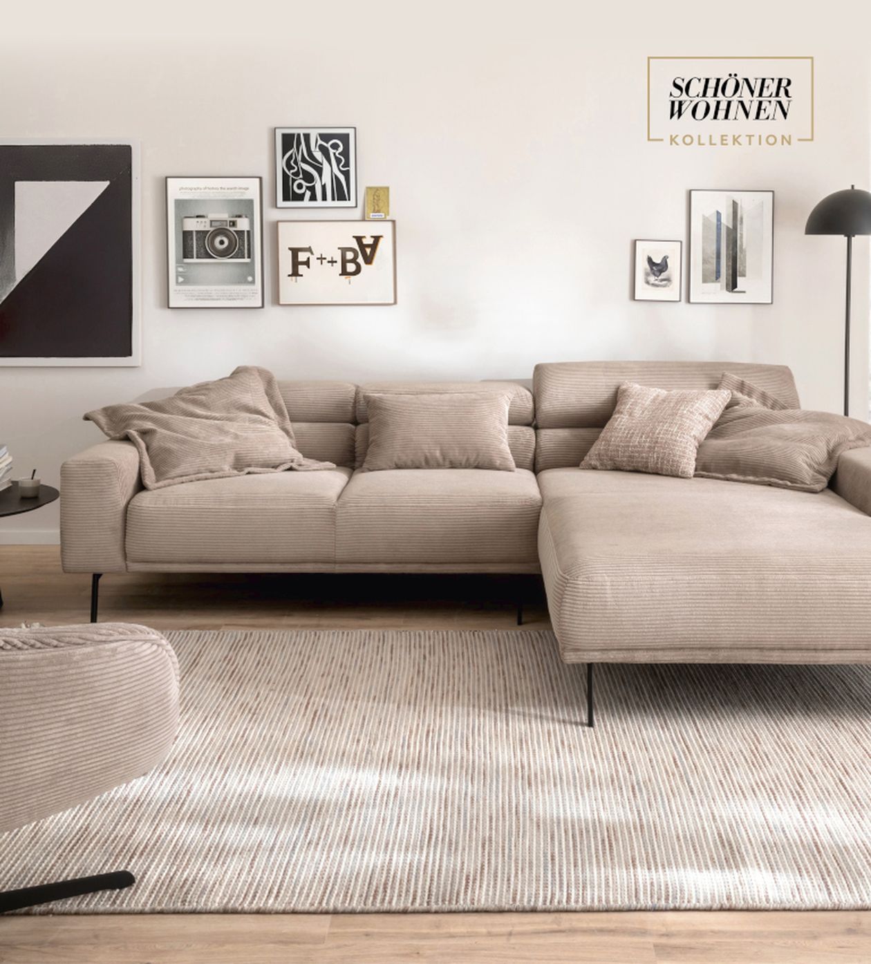Helles Wohnzimmer mit beigem Sofa, dekoriert mit Kissen, Wandbildern und Lampe. Teppich in sanften Tönen auf Holzboden.