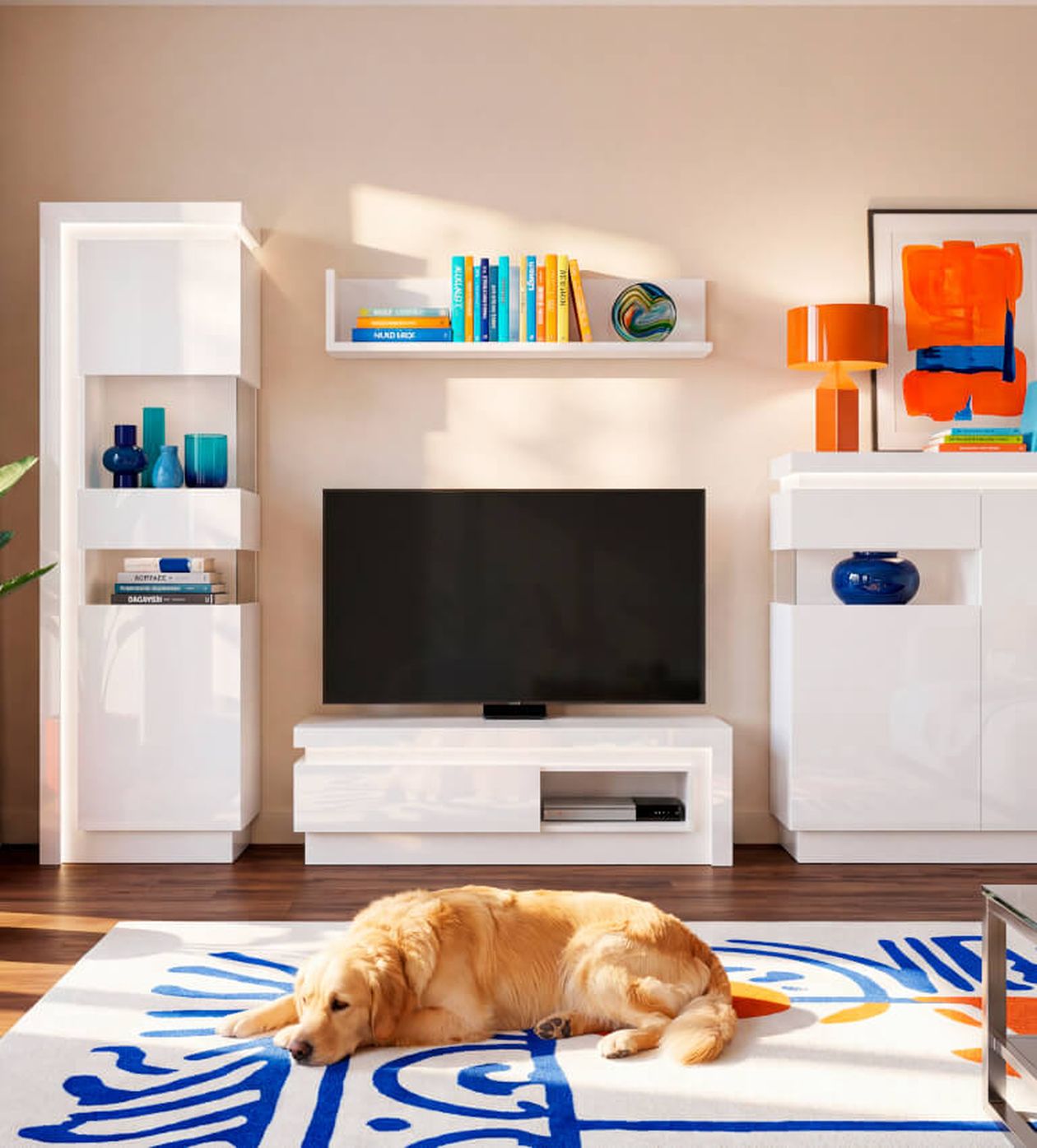 Gemütliches Wohnzimmer mit einem schlafenden Hund auf einem blau gemusterten Teppich, modernen weißen Möbeln, Fernseher, bunten Büchern, Vasen und orangefarbenen Lampen.
