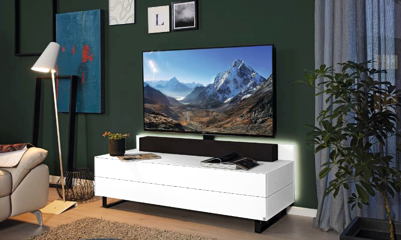 Modernes Wohnzimmer mit einem an der Wand montierten Fernseher mit einer Bergszene, einer weißen Konsole, grünen Wänden, Kunstwerken und einer Stehlampe.