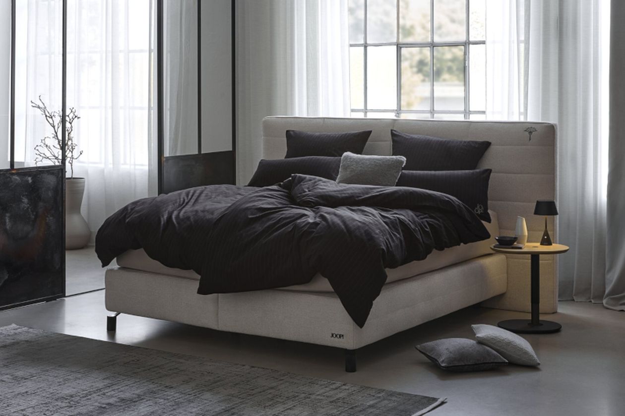 Produktbild: Gestreifte Bettwäsche der Marke JOOP! auf einem Bett in einem hellen Schlafzimmer.