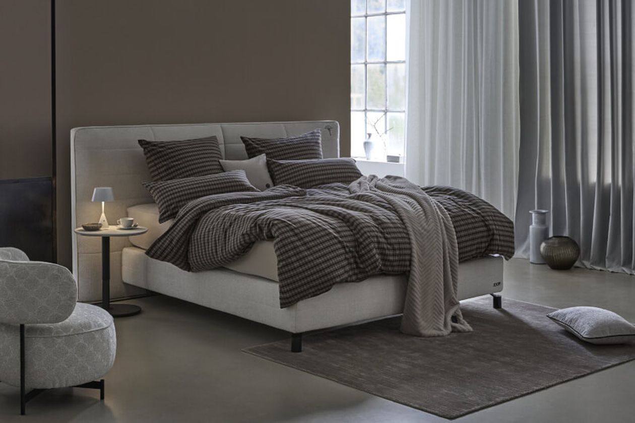 Produktbild: Karierte Bettwäsche der Marke JOOP! auf einem Bett in einem modernen Schlafzimmer.