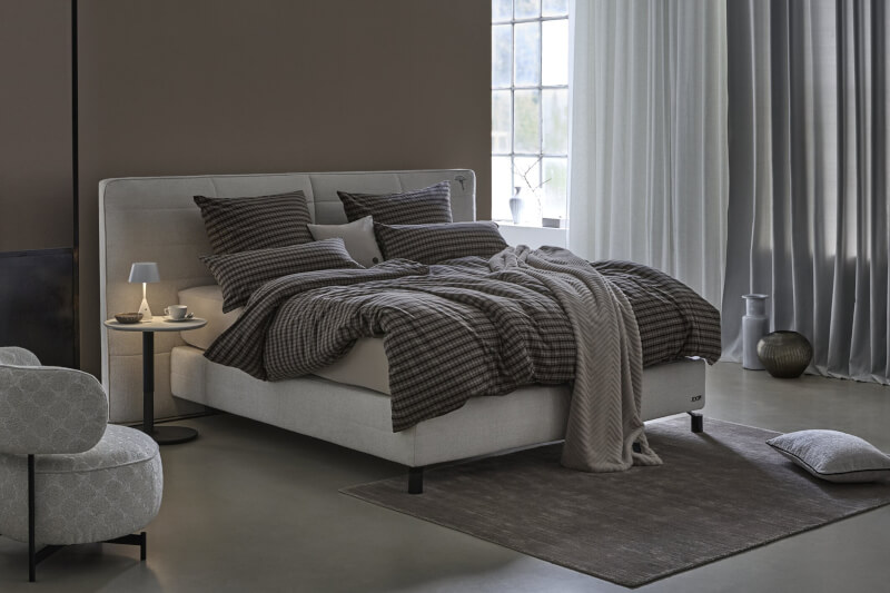 Produktbild: Karierte Bettwäsche der Marke JOOP! auf einem Bett in einem modernen Schlafzimmer.