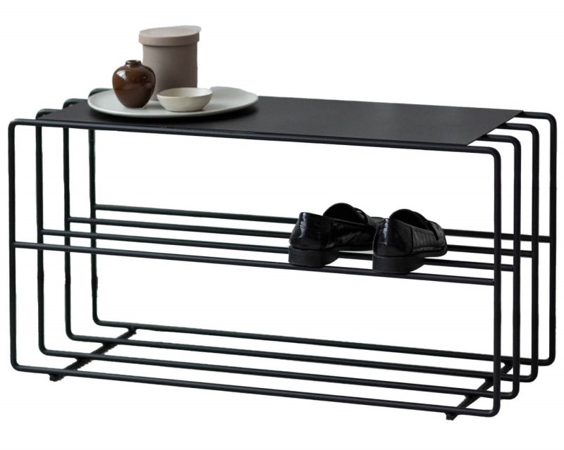 Ein minimalistisches schwarzes Metall-Schuhregal , auf welchem ein Paar schwarze Schuhe und Deko steht.