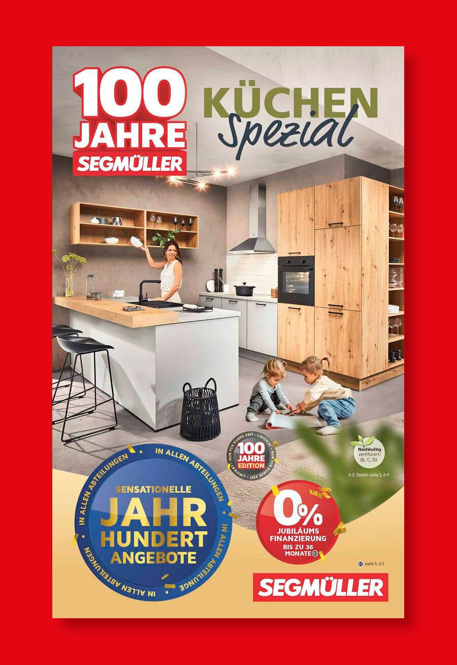 Werbung für das 100-Jahre-Küchen-Special von Segmüller mit modernem Küchendesign und zwei spielenden Kindern auf dem Boden.