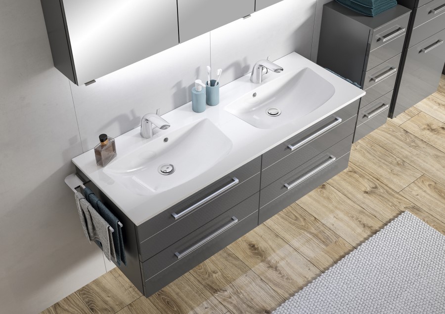 Modernes Badezimmer mit Doppelwaschbecken, grauen Schubladen, Pflegeprodukten und einem Handtuch an der Seite, auf einem Holzboden mit Teppich.