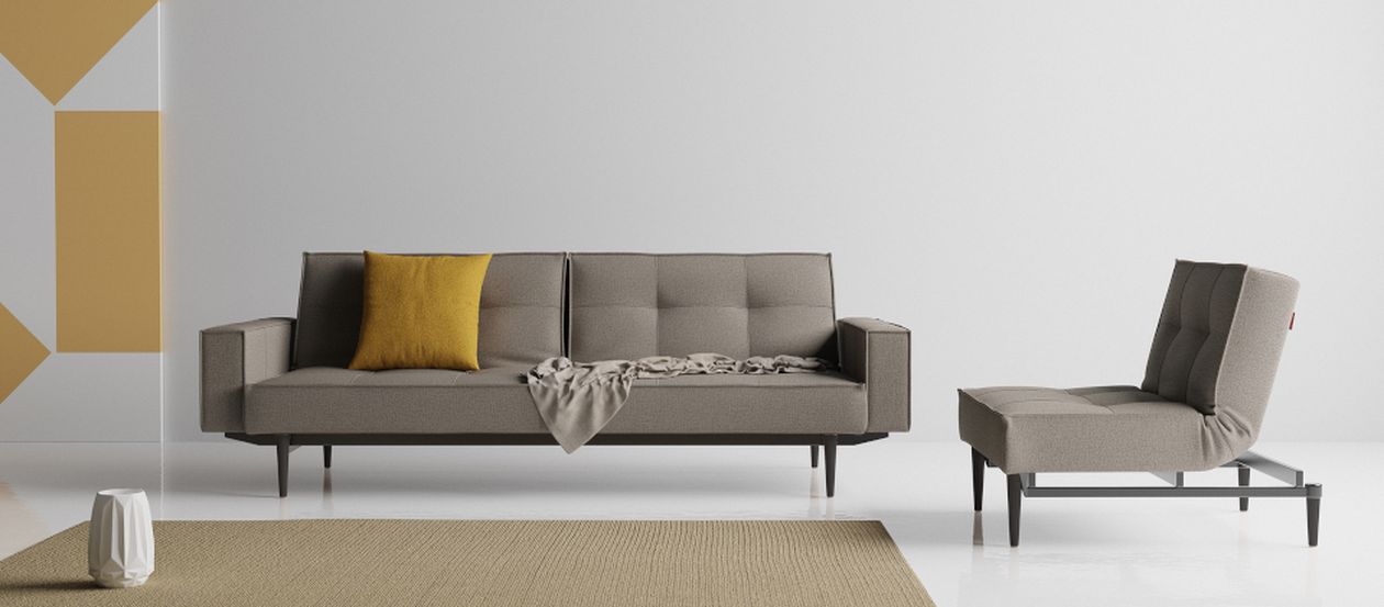 Graues Sofa mit gelbem Kissen und Decke, kombiniert mit einem passenden Sessel in einem minimalistischen Wohnzimmer.