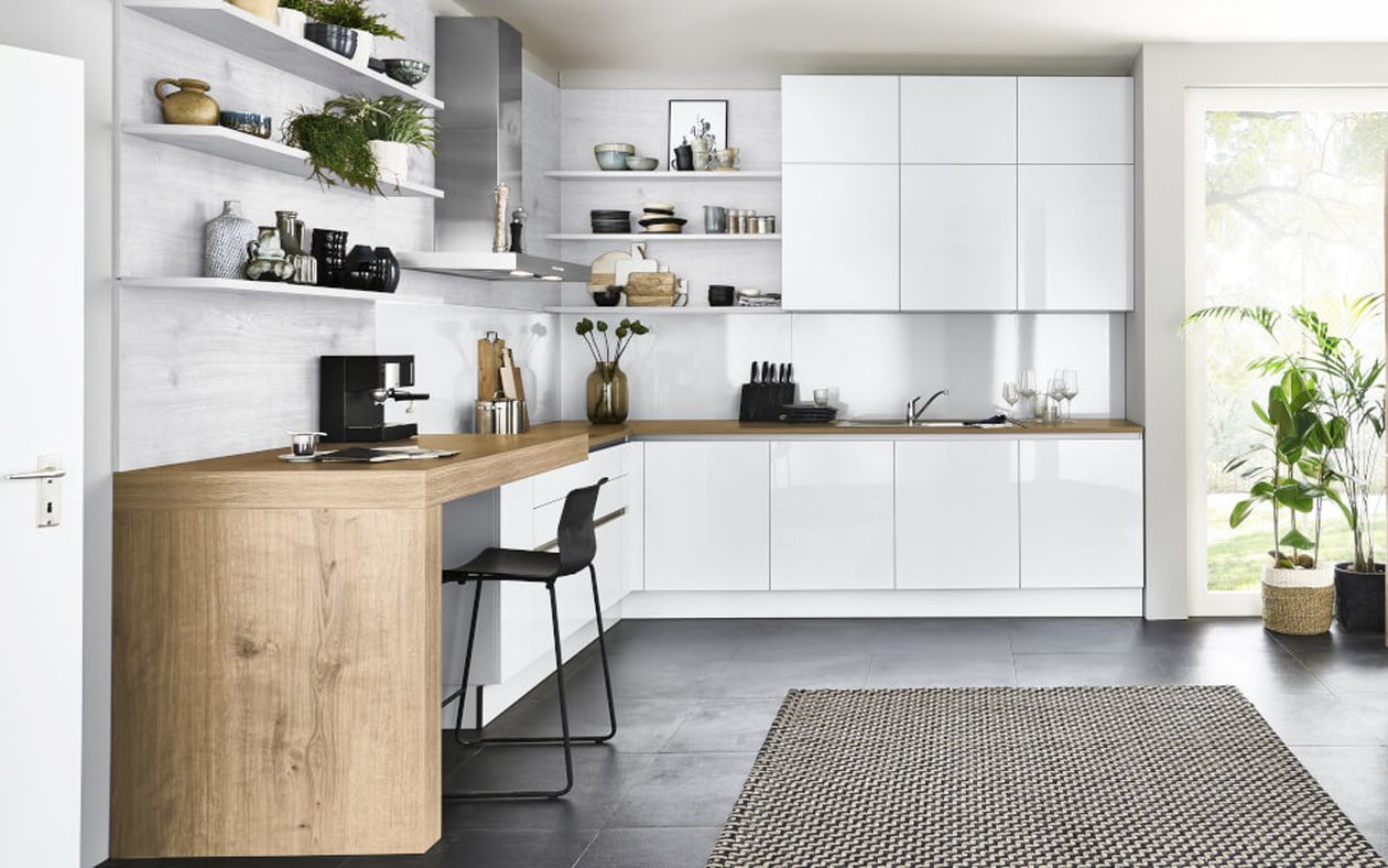 Moderne Küche mit weißen Schränken, Holzarbeitsplatte, offenen Regalen mit Pflanzen, einem schwarzen Barhocker und Fliesenboden. Großes Fenster mit Pflanzen.