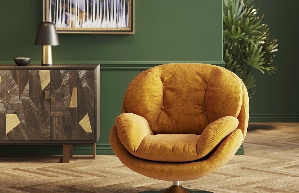 Ein gemütlicher, runder, orangefarbener Sessel in einem stilvollen Wohnzimmer mit grünen Wänden, Holzschrank, kleiner Lampe und einem gerahmten Kunstwerk.