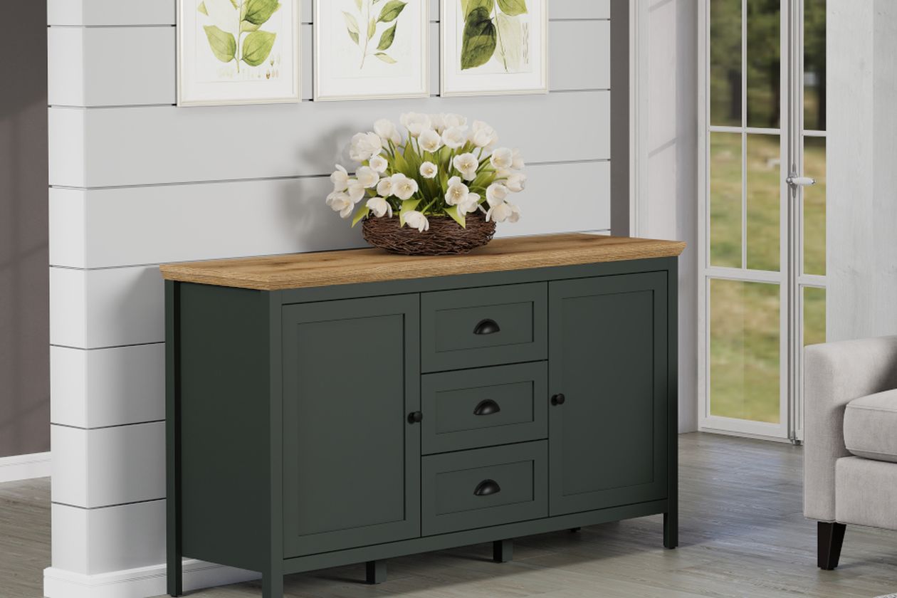 Sideboard in Dunkelgrün mit Holzplatte, drei Schubladen und weißer Blumenarrangement-Deko. Weiße Wand mit botanischen Bildern und Blick zur Terrassentür.