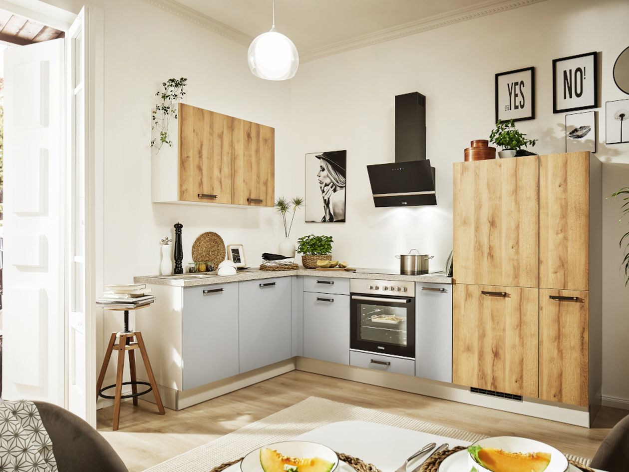 Helle, L-förmige Küche mit hellen Holzschränken und grauen Unterschränken, Edelstahl-Backofen und Dunstabzugshaube, Topfpflanzen, Holzhocker und gerahmten Wandbildern.