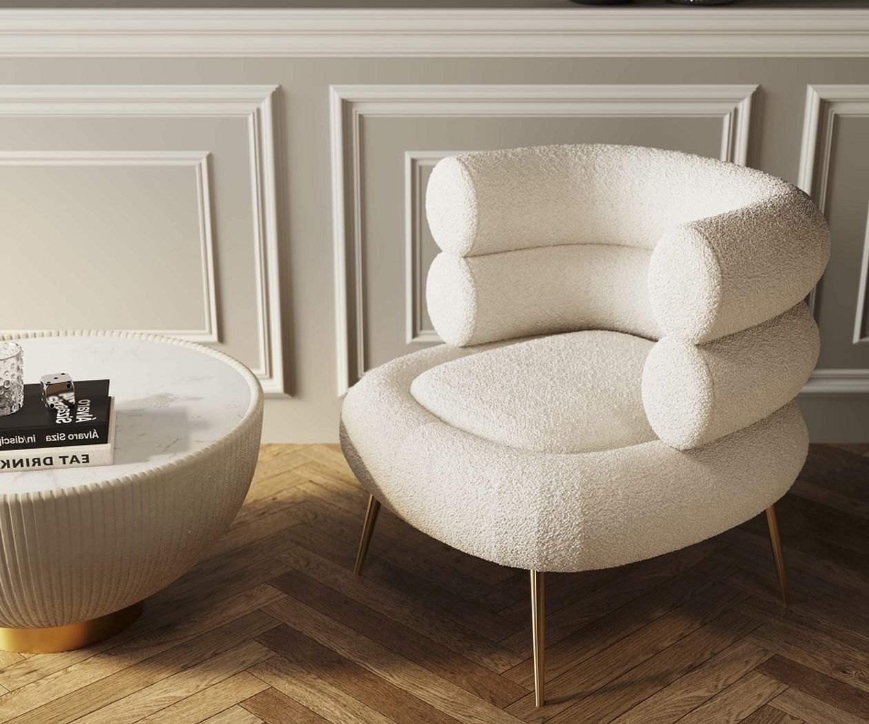 Ein moderner weißer Bouclé-Sessel mit zylindrischen Kissen und goldenen Beinen steht neben einem runden Couchtisch auf einem Fischgrätparkettboden vor getäfelten Wänden.